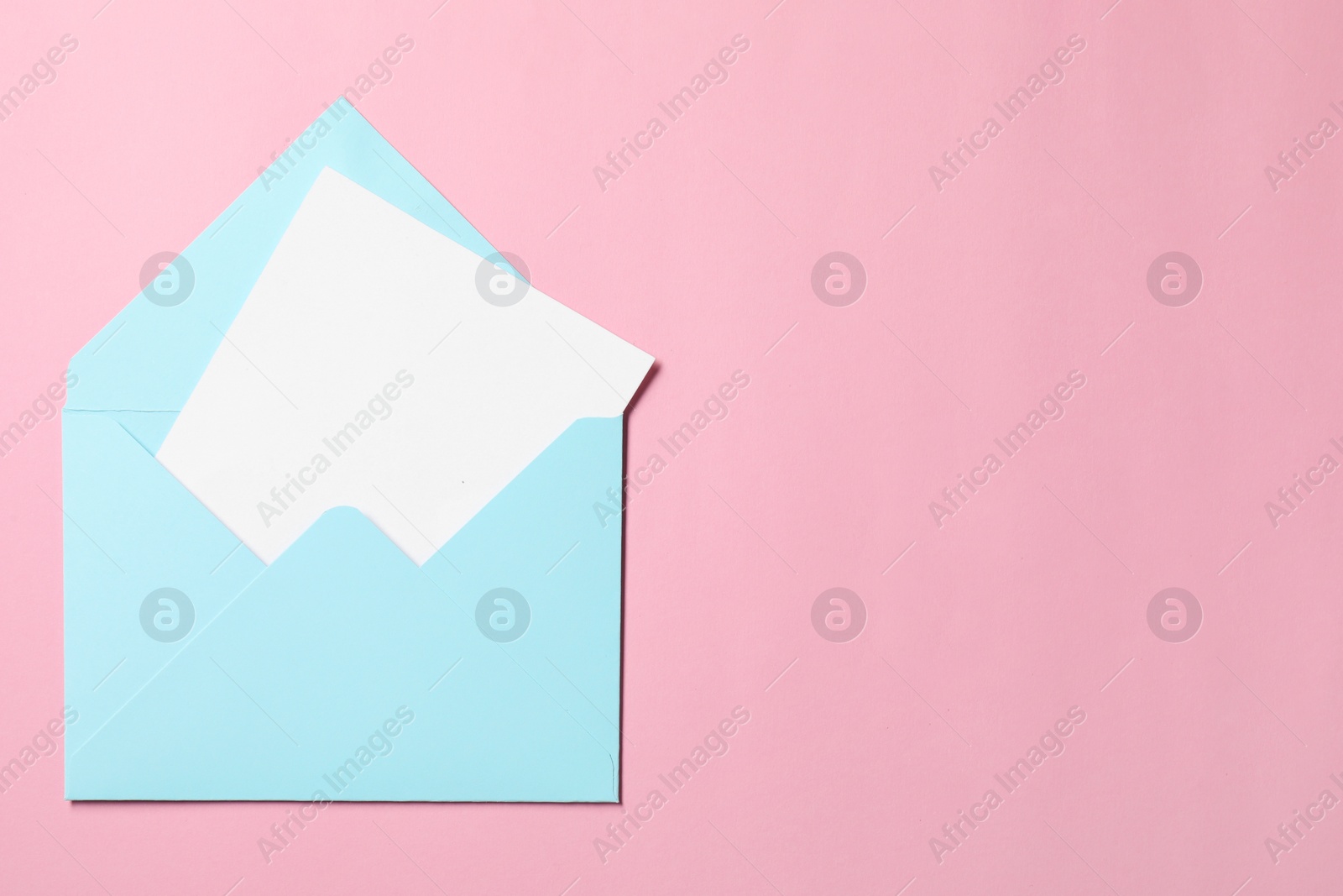 Photo of Letter envelope with card on pink background, top view. Space for text