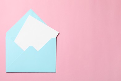 Letter envelope with card on pink background, top view. Space for text