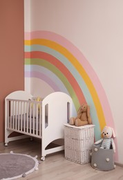 Photo of Cute child's room interior with beautiful rainbow painted on wall