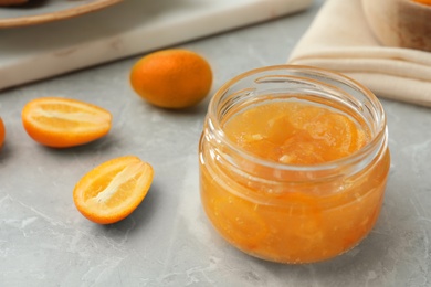 Delicious kumquat jam and fresh fruits on light grey marble table