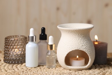 Different aromatherapy products and burning candles on table