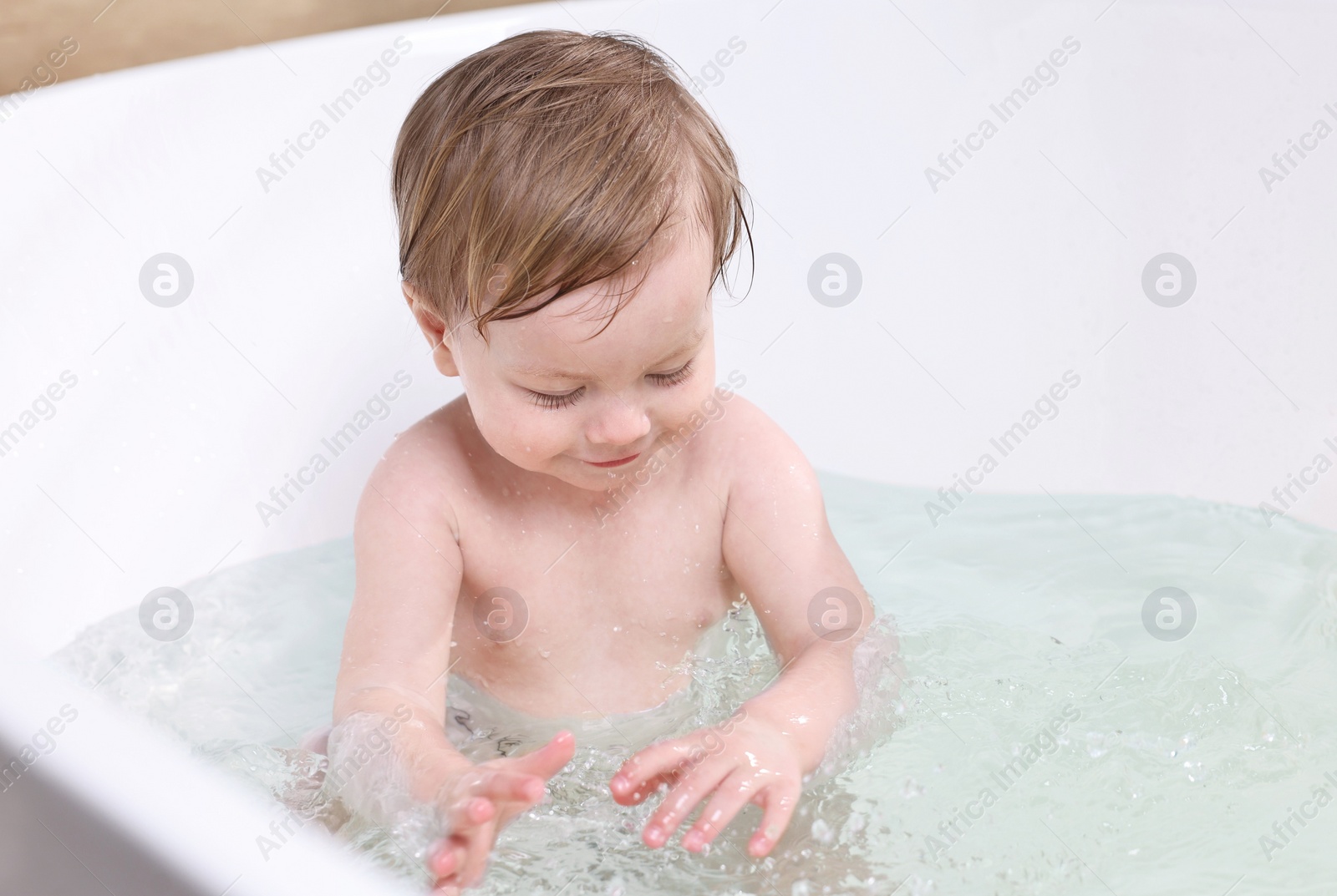 Photo of Cute little child bathing in tub at home