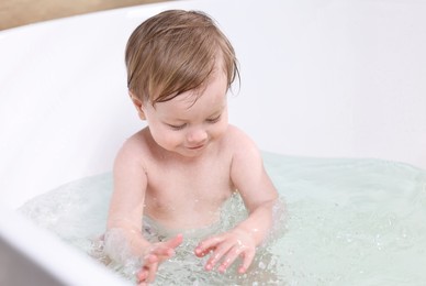 Cute little child bathing in tub at home