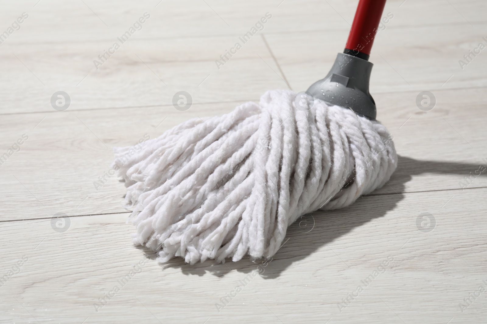 Photo of Cleaning white parquet floor with mop, closeup