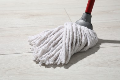 Cleaning white parquet floor with mop, closeup