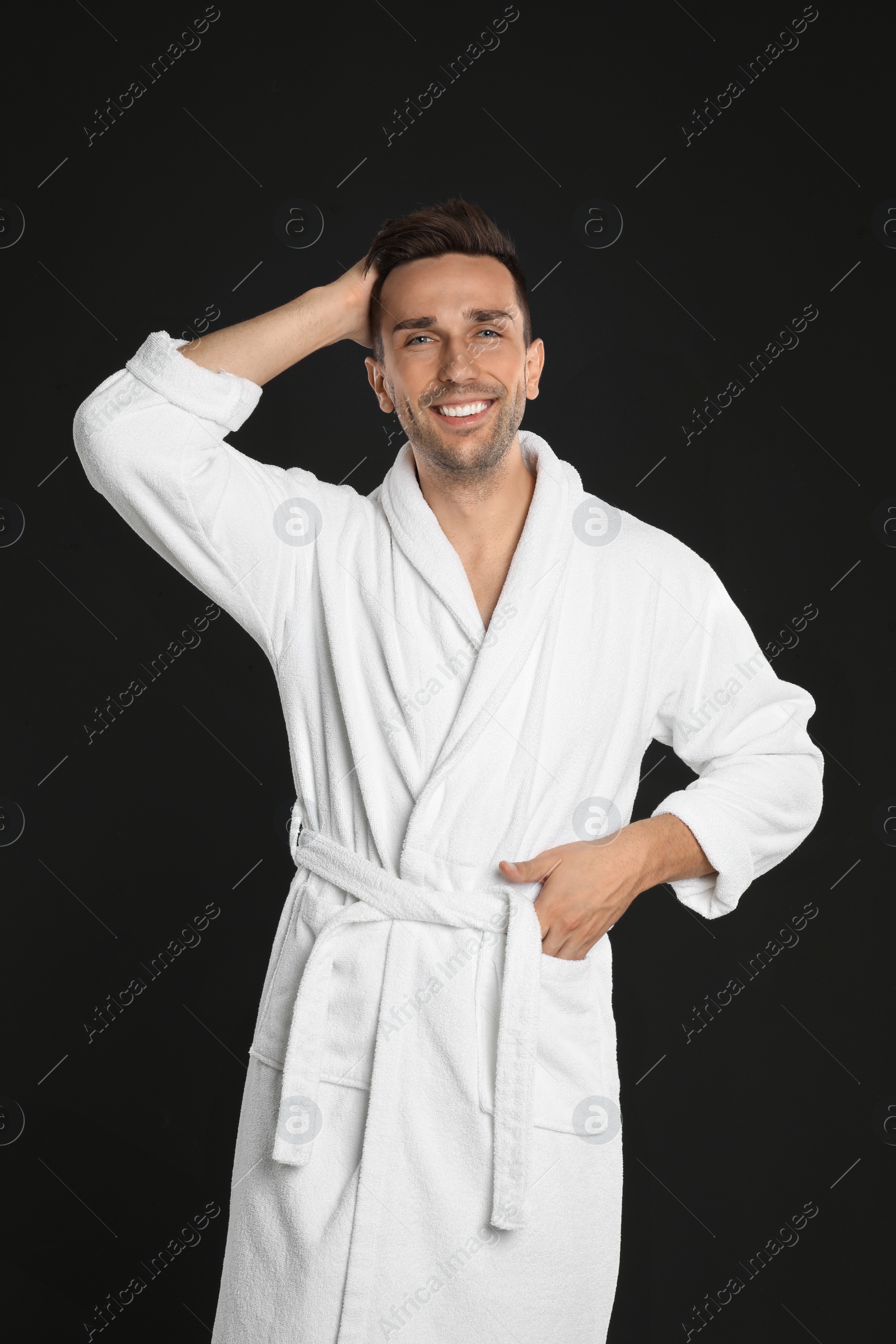 Photo of Happy young man in bathrobe on black background