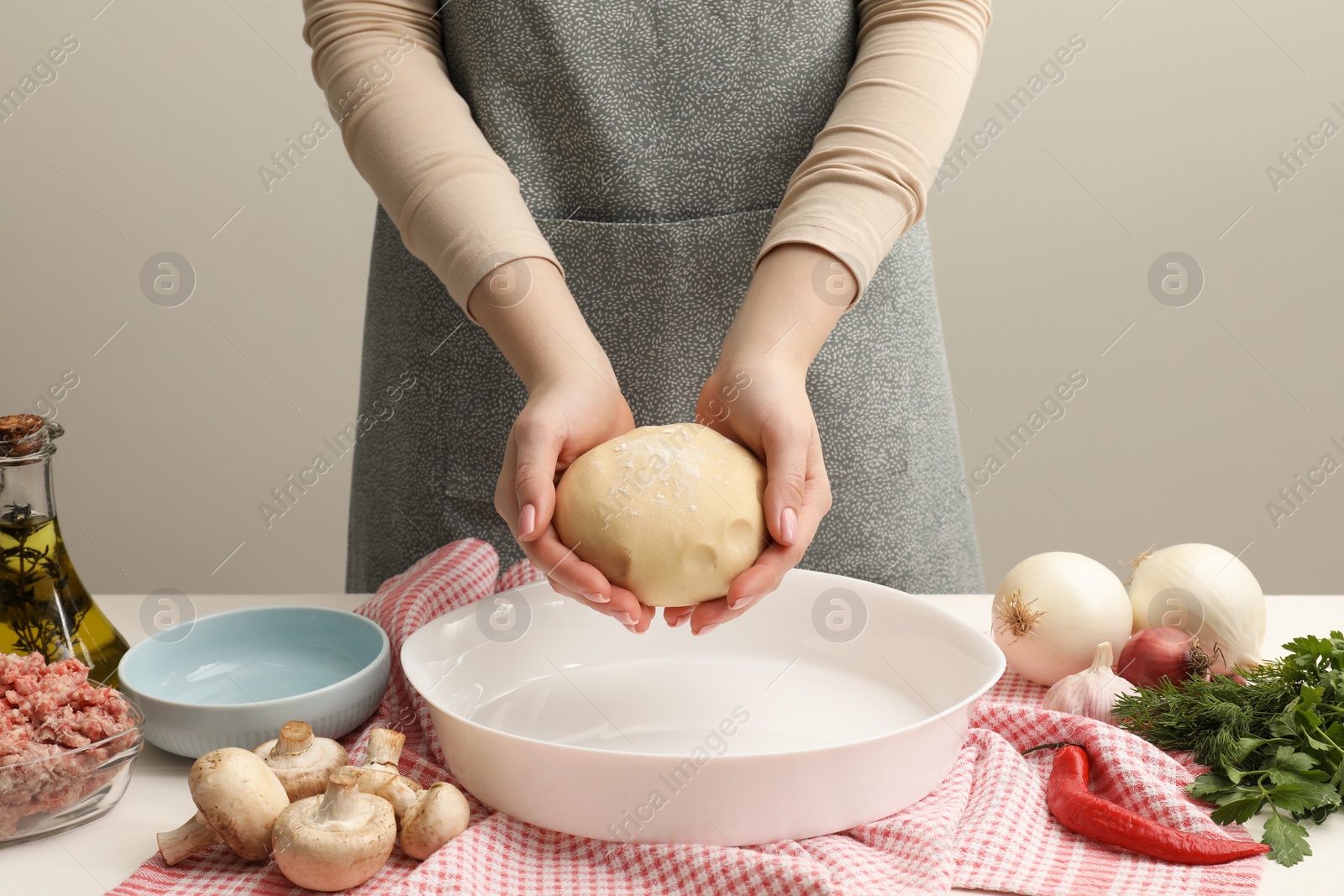 Photo of Woman making meat pie at white table, closeup