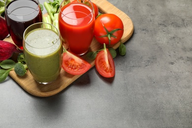 Photo of Delicious vegetable juices and fresh ingredients on grey table. Space for text