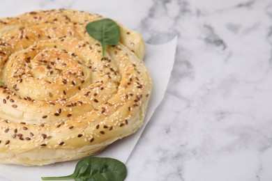 Photo of Delicious puff pastry with spinach on white marble table, closeup. Space for text