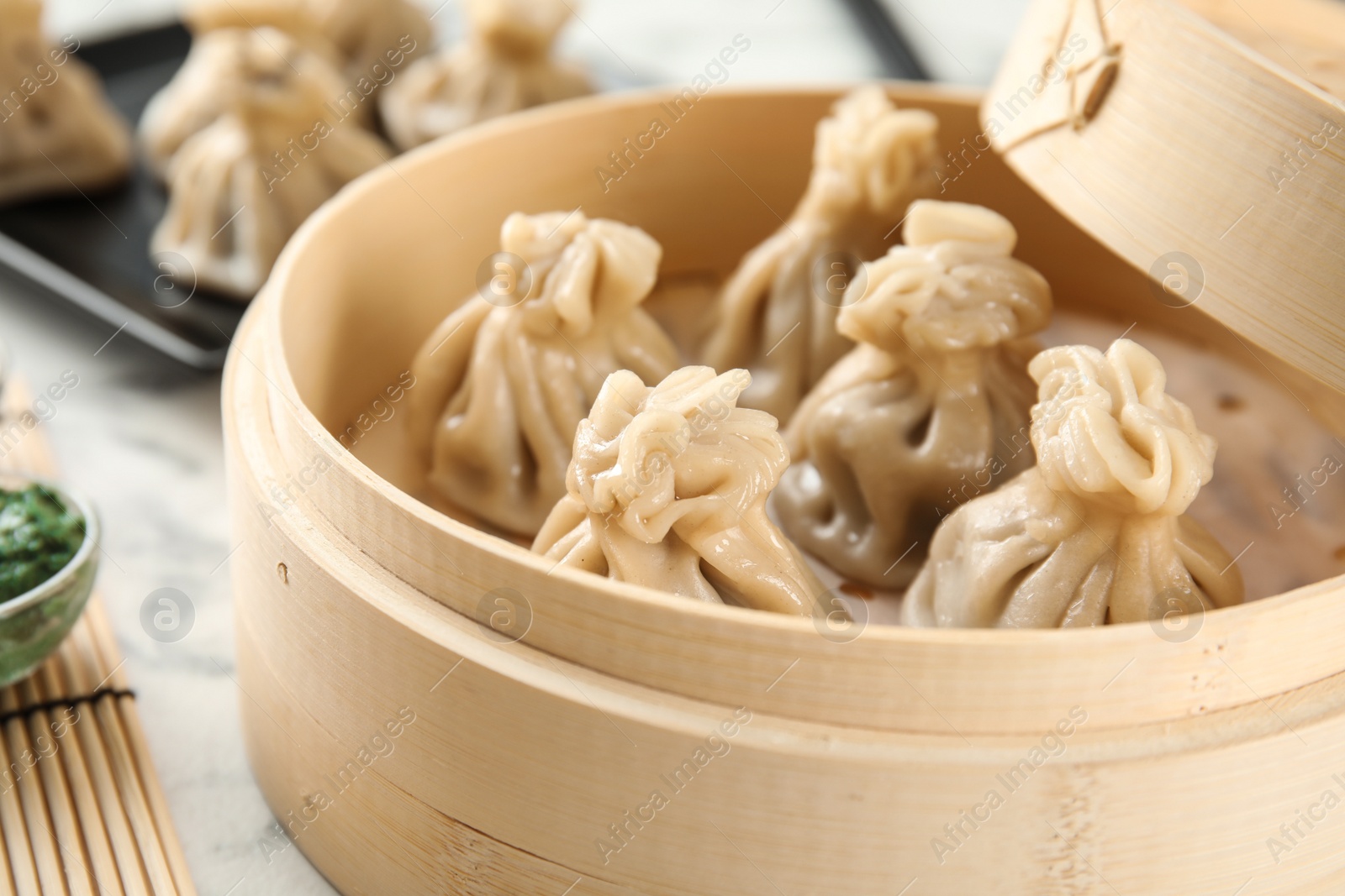 Photo of Bamboo steamer with tasty baozi dumplings on table, closeup