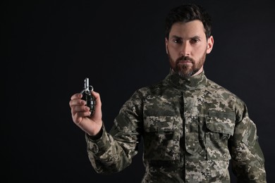 Photo of Soldier holding hand grenade on black background. Military service
