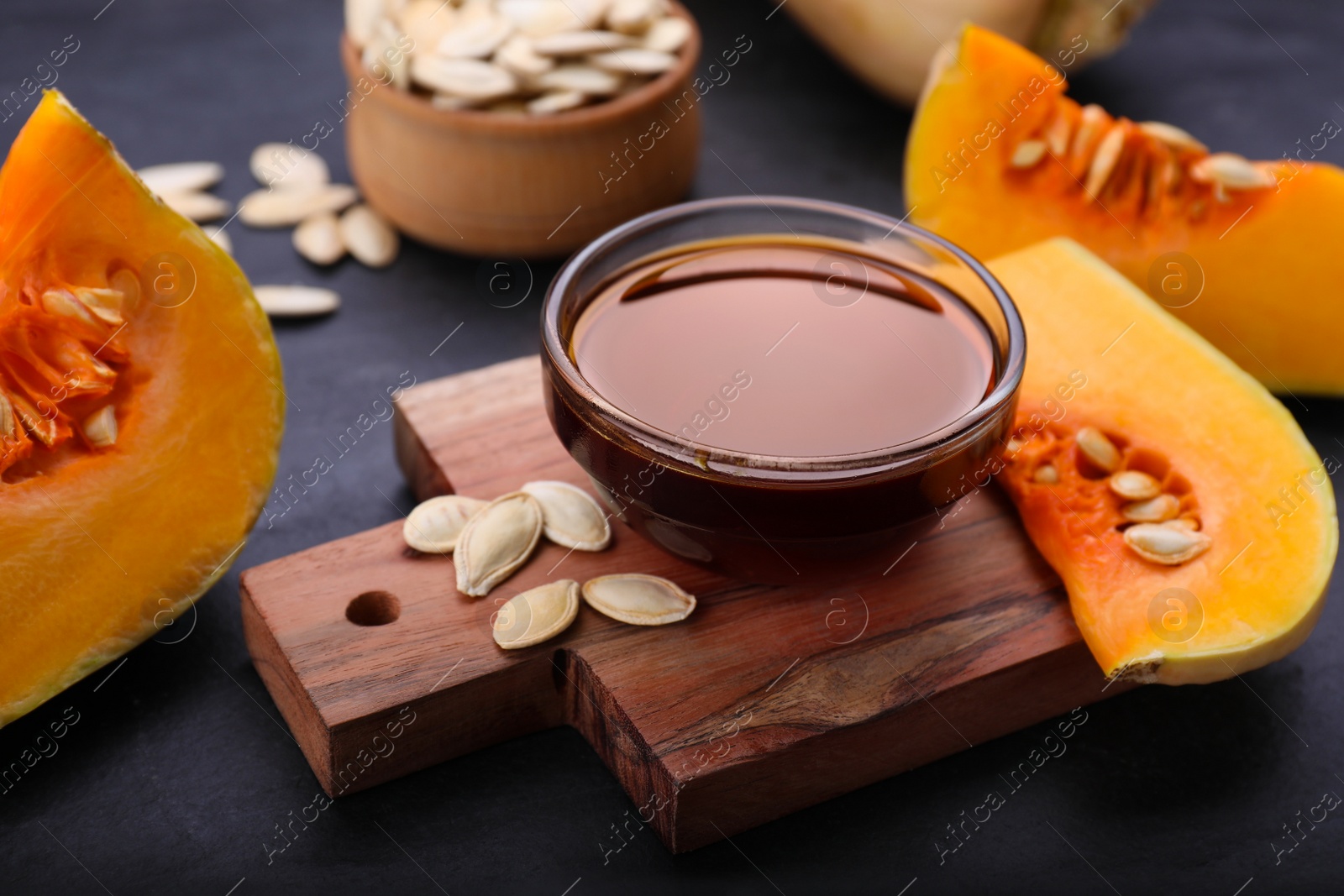 Photo of Glass bowl of pumpkin seed oil on dark grey table