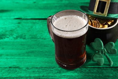 St. Patrick's day. Beer, leprechaun hat, pot of gold and decorative clover leaf on green wooden table. Space for text