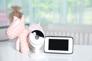 Photo of Baby monitor with camera and toy on table in room. Video nanny