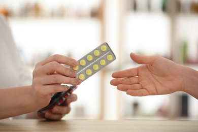Pharmacist giving medicine to customer in drugstore, closeup
