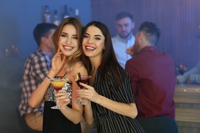 Beautiful young women with martini cocktails in bar
