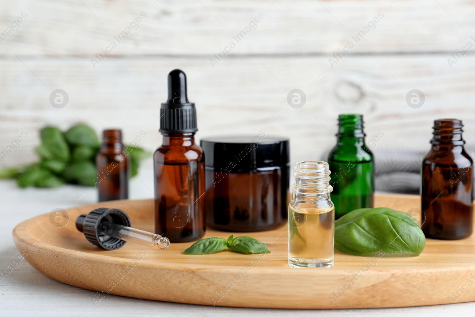 Photo of Composition with bottles of essential oils and basil on table