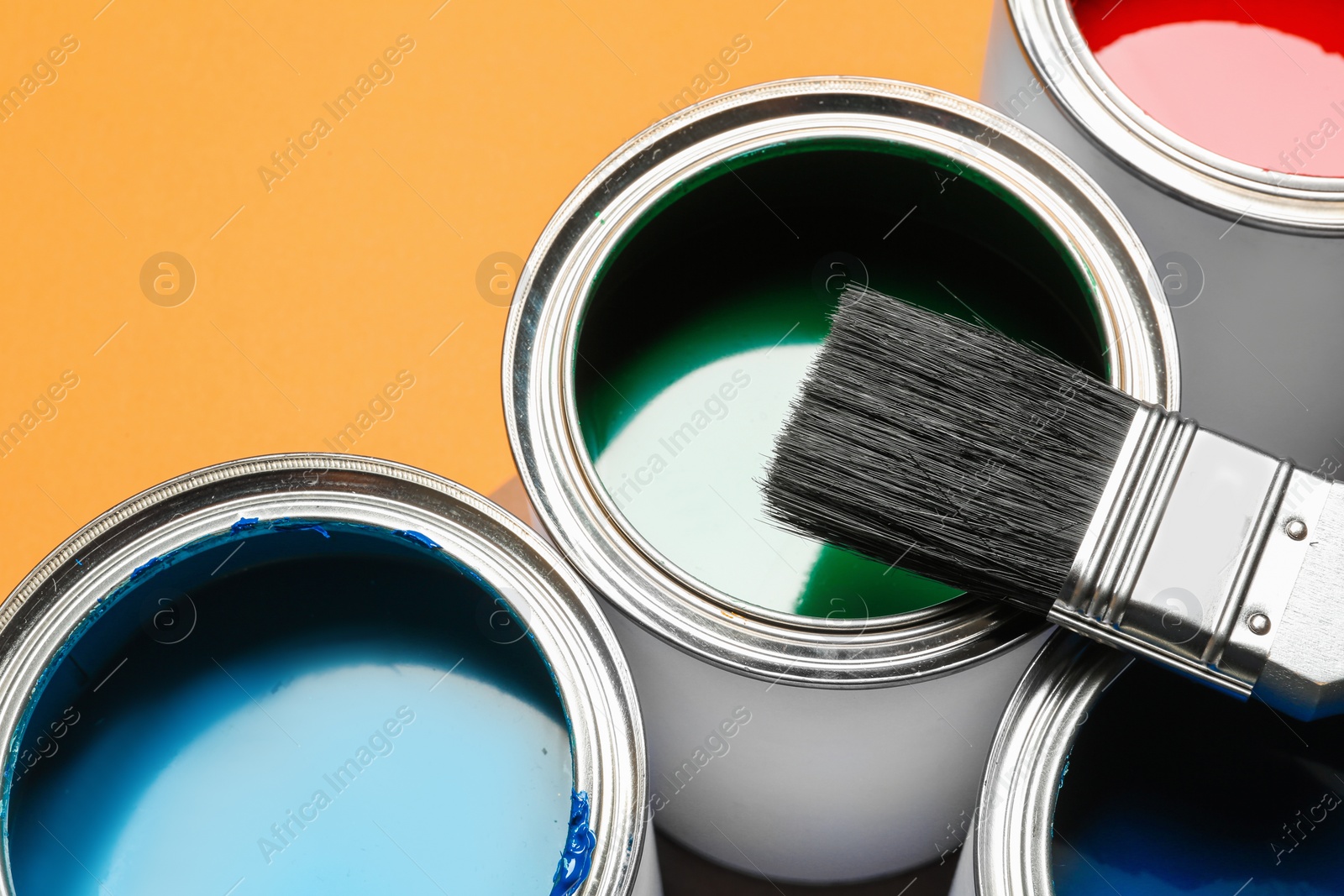 Photo of Closeup view of paint cans and brush on color background