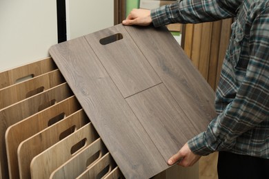 Photo of Man with sample of wooden flooring in shop, closeup