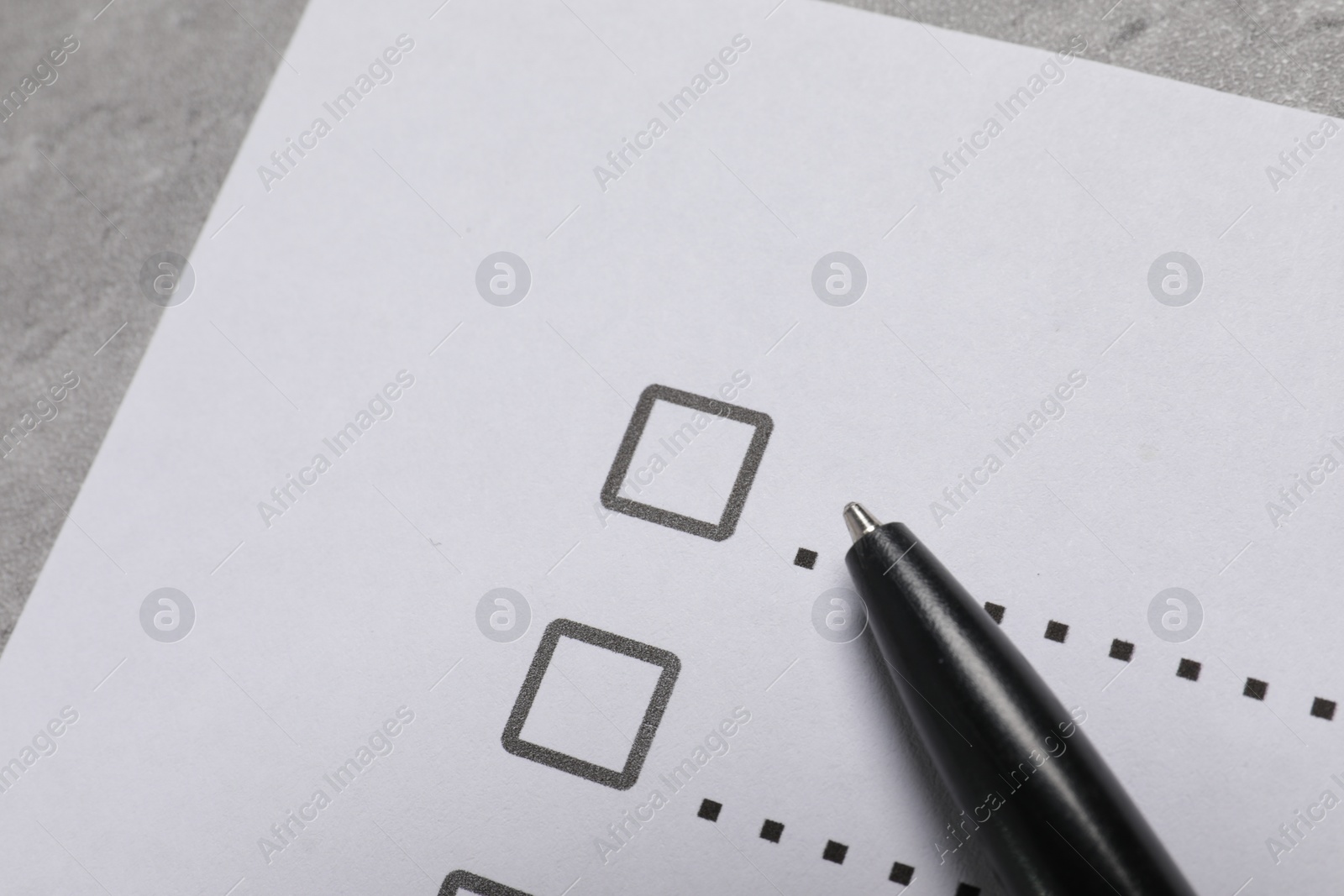 Photo of Paper sheet with checkboxes and pen on light grey table, closeup. Checklist