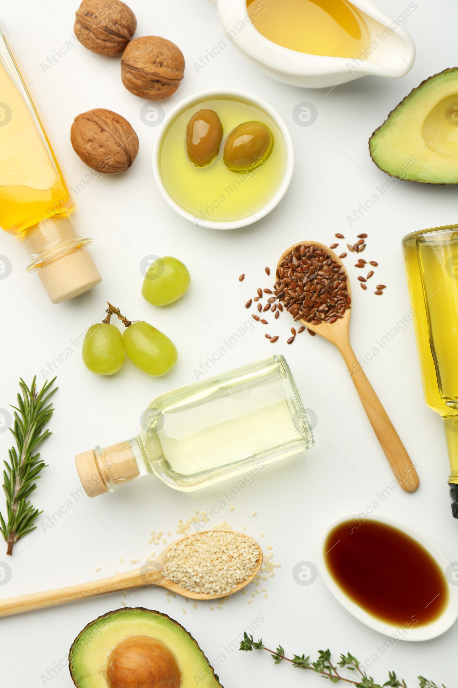 Photo of Vegetable fats. Different oils in glass bottles and ingredients on white table, flat lay