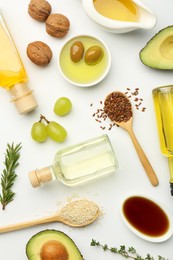 Photo of Vegetable fats. Different oils in glass bottles and ingredients on white table, flat lay