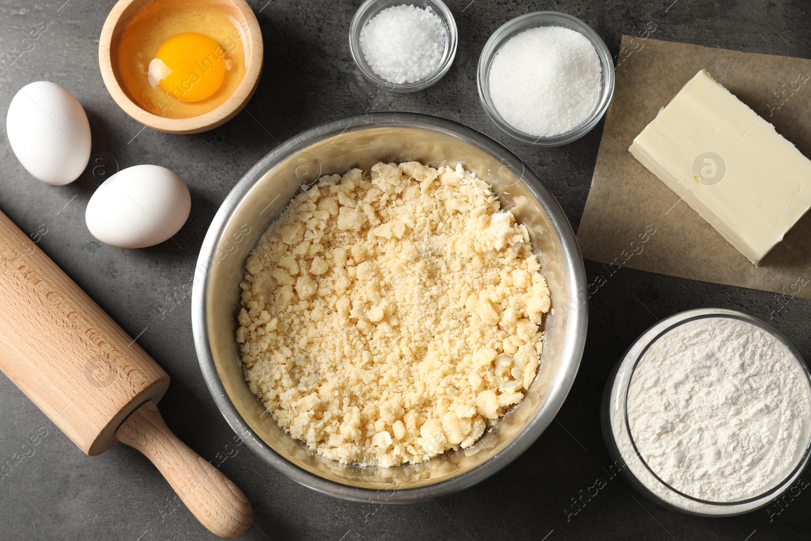 Photo of Making shortcrust pastry. Different ingredients for dough and rolling pin on grey table, flat lay