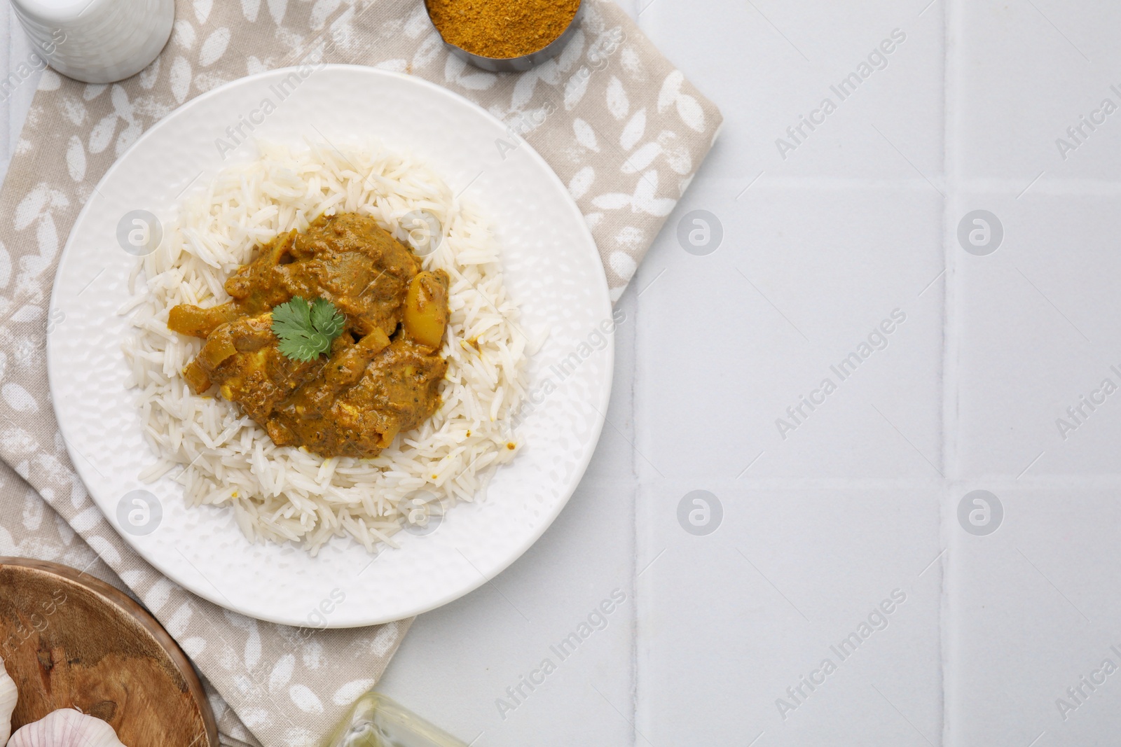 Photo of Delicious chicken curry with rice and ingredients on white tiled table, flat lay. Space for text