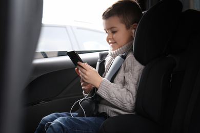 Photo of Cute little boy listening to audiobook in car