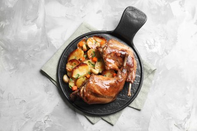 Tasty cooked rabbit meat with vegetables on light grey table, top view