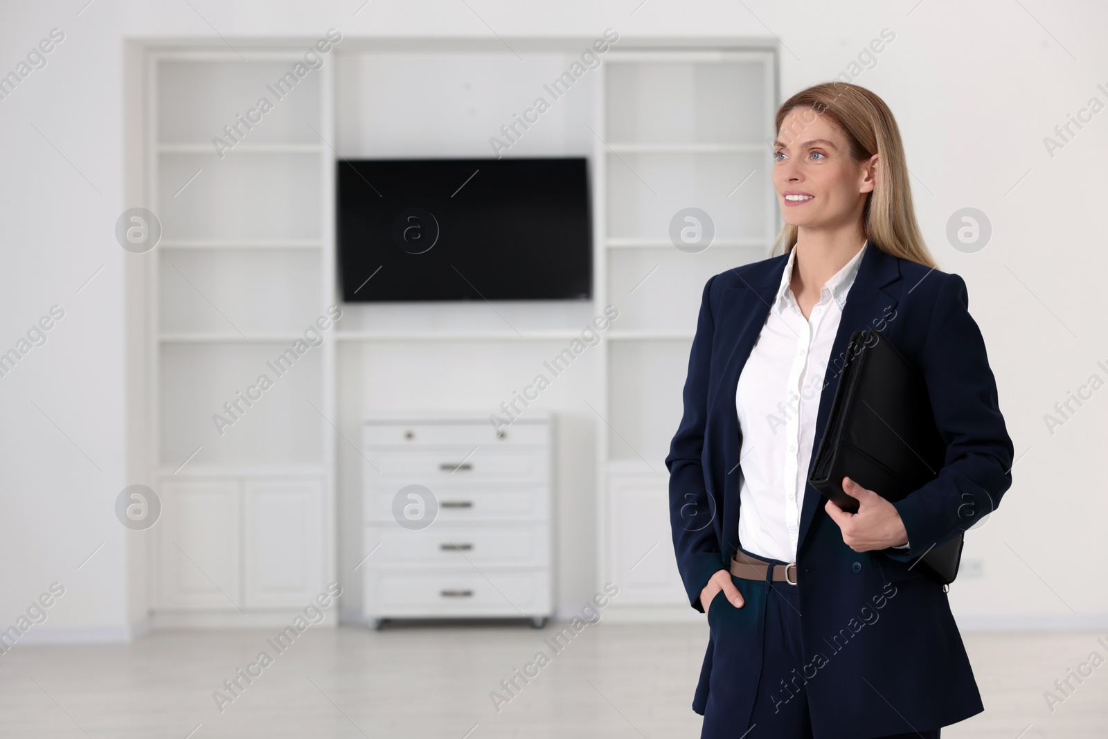 Photo of Happy real estate agent with leather portfolio in new apartment