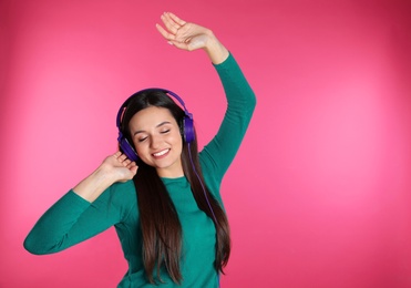 Photo of Attractive young woman enjoying music in headphones on color background. Space for text