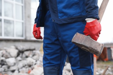 Man in uniform with sledgehammer outdoors, closeup