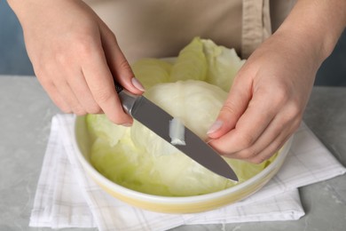 Photo of Woman preparing stuffed cabbage rolls at light grey table, closeup