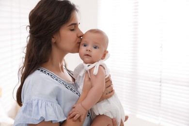 Happy young mother with her cute baby near window at home