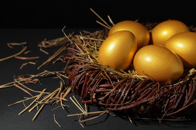 Shiny golden eggs in nest on black background. Space for text