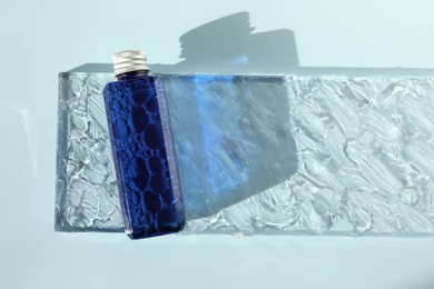 Photo of Bottle of cosmetic product on light blue background, top view