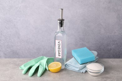 Natural cleaning products. Vinegar in bottle, baking soda, lemon, glove and sponge on light grey table