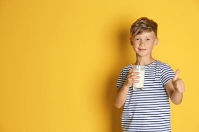 Photo of Adorable little boy with glass of milk on color background