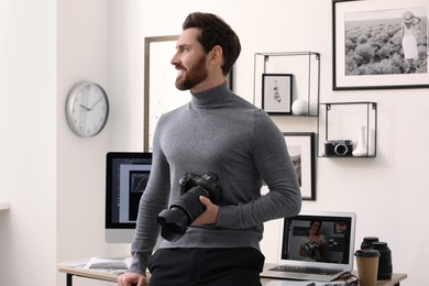 Professional photographer with digital camera near table in office
