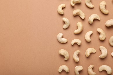 Many tasty cashew nuts on pale brown background, top view. Space for text