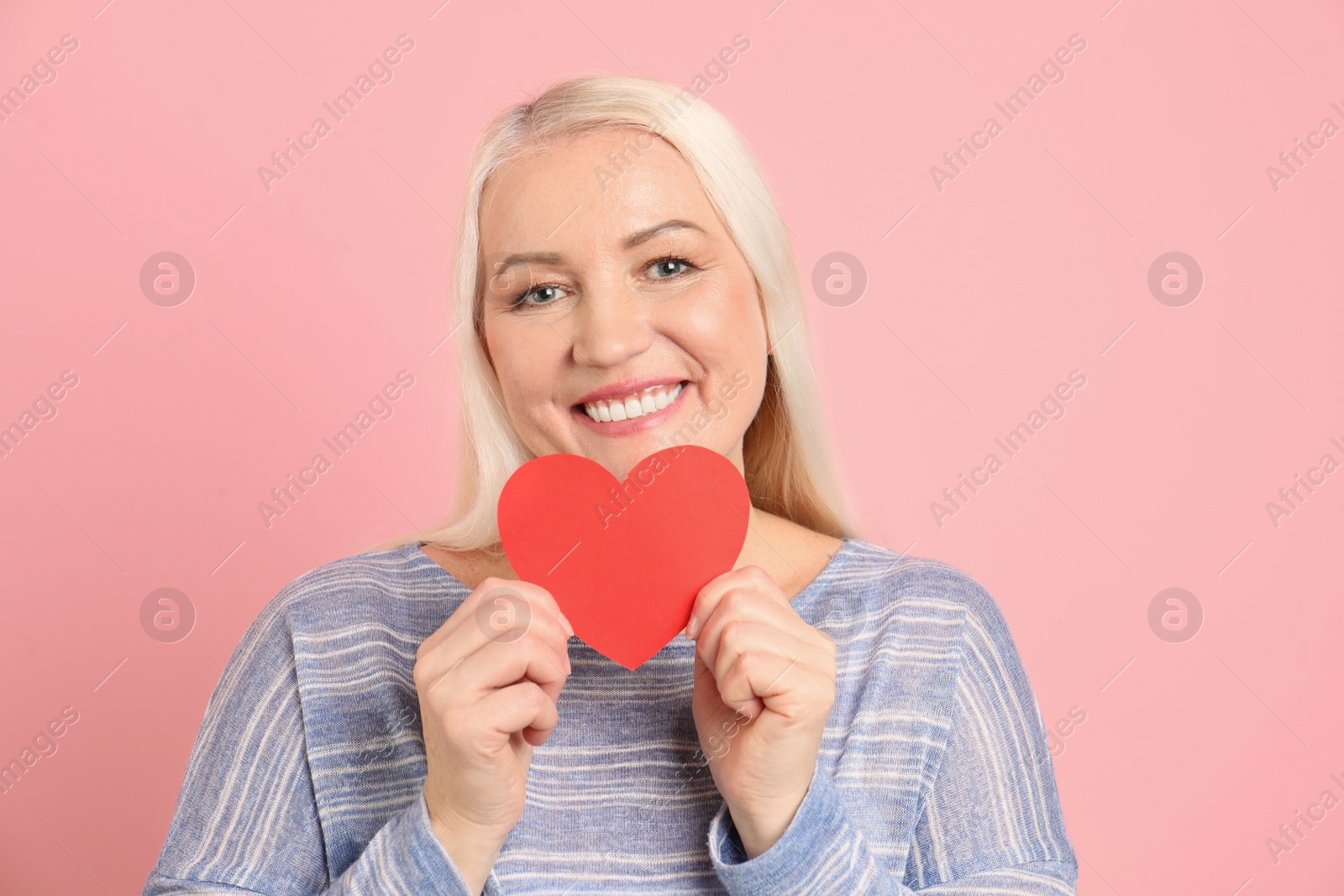 Photo of Portrait of mature woman with decorative paper heart on color background