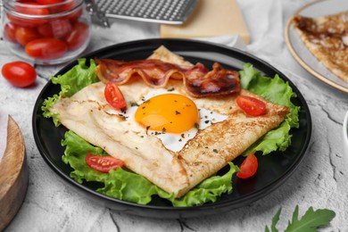 Photo of Delicious crepe with egg served on light gray textured table, closeup. Breton galette