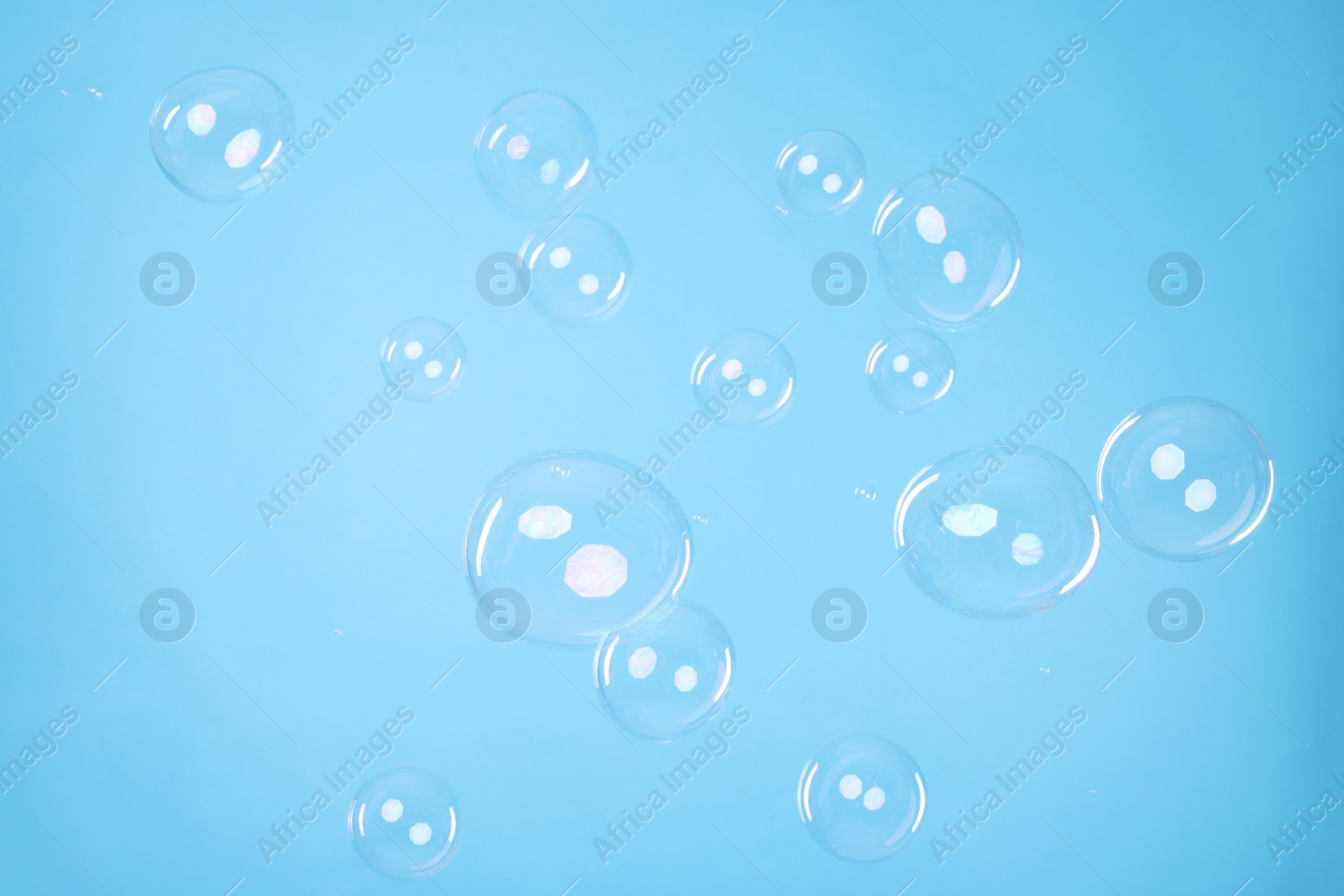 Photo of Many beautiful soap bubbles on light blue background