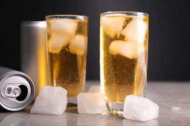 Tasty energy drink with ice cubes in glasses and aluminium cans on grey table, closeup