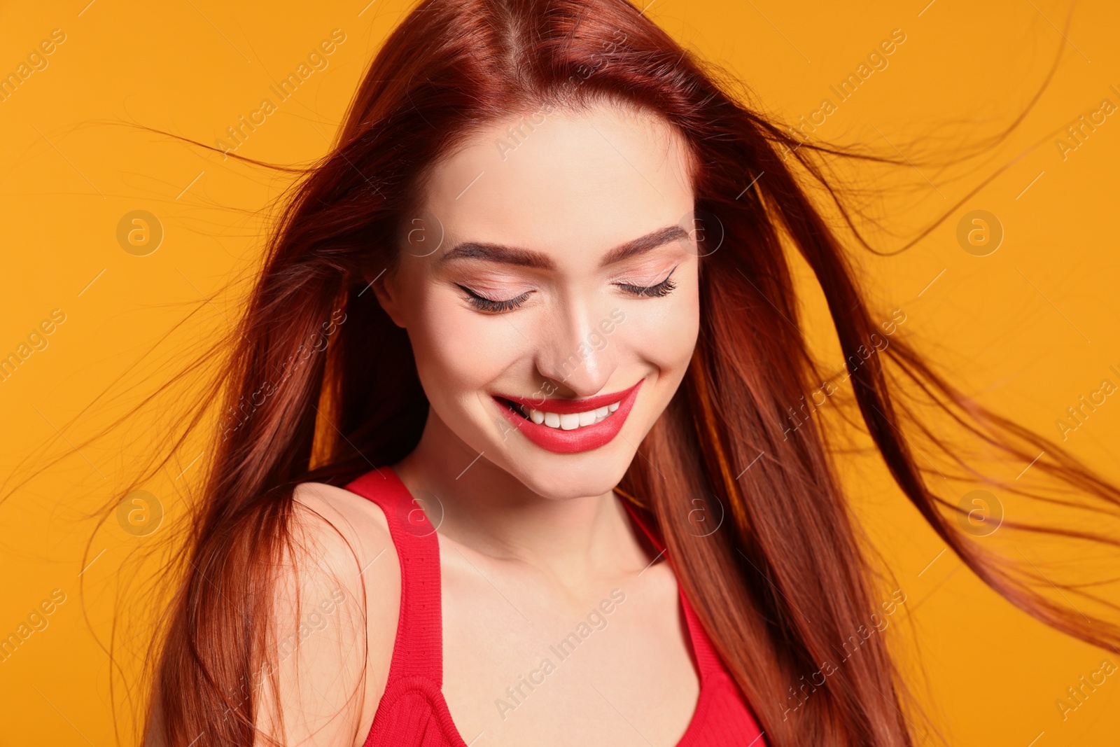 Photo of Happy woman with red dyed hair on orange background