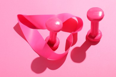 Photo of Dumbbells and fitness elastic band on pink background