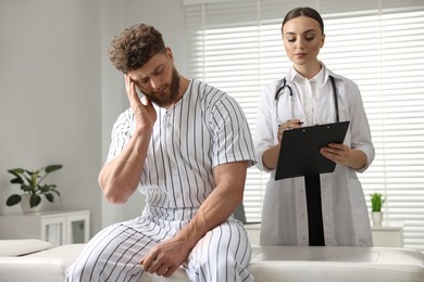 Injured sportsman and doctor with clipboard in hospital