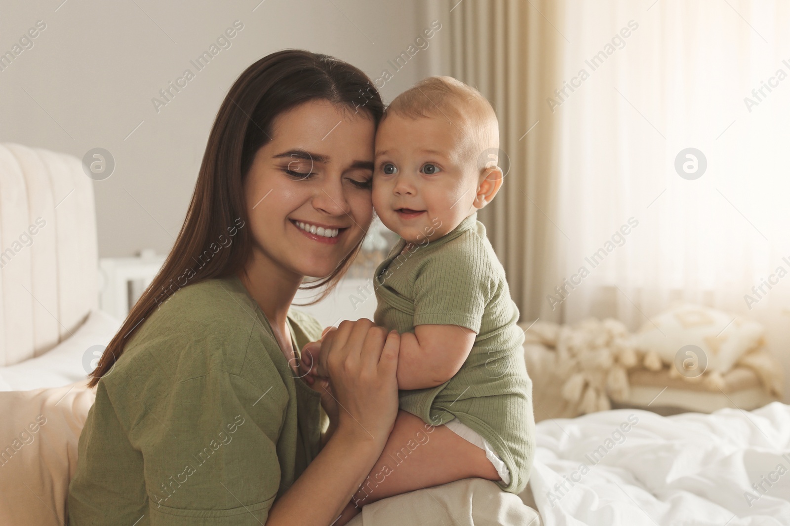 Photo of Happy young mother with her cute baby on bed at home