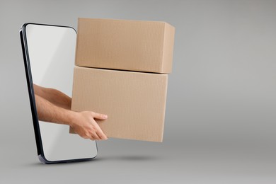 Courier passing parcels through smartphone on grey background. Delivery service